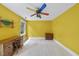 Bright yellow bedroom with desk, two windows and a quirky colorful ceiling fan at 821 Ascot Ln, Raleigh, NC 27615
