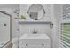 This bathroom has a white vanity, round mirror, and a shower featuring gray and white tiles at 8801 Valley Hill Ct, Apex, NC 27539