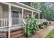 Close-up of a charming front porch with white railings, detailed trim, and lush landscaping at 8801 Valley Hill Ct, Apex, NC 27539