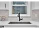 Detailed view of a black kitchen sink with a sleek faucet, set against a white countertop with a bright window view at 8801 Valley Hill Ct, Apex, NC 27539
