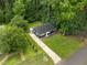 An aerial view showcases the property with its well-manicured lawn, driveway, and a charming blue home nestled among mature trees at 105 Hanna St, Carrboro, NC 27510