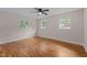 Bright bedroom featuring hardwood floors, a ceiling fan, and natural light from three windows at 105 Hanna St, Carrboro, NC 27510