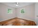 Sunlit bedroom with hardwood floors, a ceiling fan, and two bright windows at 105 Hanna St, Carrboro, NC 27510