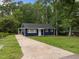 Charming blue single-story home featuring a long driveway, lush lawn, and surrounded by mature trees at 105 Hanna St, Carrboro, NC 27510