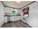 Charming kitchen features white cabinetry, appliances, wood flooring, and natural wood beams at 105 Hanna St, Carrboro, NC 27510