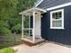 Close-up of the covered side porch on this blue home, showcasing brick steps and white railings at 105 Hanna St, Carrboro, NC 27510