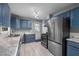 Functional kitchen featuring blue cabinets, stainless steel appliances, and a door to backyard at 110 Starlite Dr, Carrboro, NC 27510