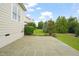 Stone patio extends from the home and overlooks the well-manicured backyard and lush landscaping at 121 Hardy Oaks Way, Holly Springs, NC 27540