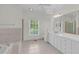 Bright bathroom featuring tiled floors, a large mirror, and a window with natural light at 280 Phillips Rd, Selma, NC 27576