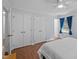 Bedroom with hardwood floors, a ceiling fan, blue curtains, and dual closets for a comfortable living space at 3007 Appling Way, Durham, NC 27703