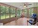 Bright sunroom with walls of windows overlooking lush backyard, with blue chairs and wood-style laminate flooring at 3007 Appling Way, Durham, NC 27703