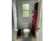 A small bathroom with white walls, a toilet, beadboard paneling, and a red and black curtain at 3129 Skycrest Dr, Raleigh, NC 27604