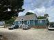 View of the house with blue siding, gravel driveway, and several cars parked out front at 3129 Skycrest Dr, Raleigh, NC 27604