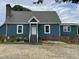 Charming blue house with white trim, brick foundation and chimney, and a gravel driveway at 3129 Skycrest Dr, Raleigh, NC 27604