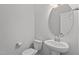 A half bathroom features a pedestal sink and modern round mirror at 319 Great Northern Station Sta, Apex, NC 27502