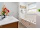 Bright, white-tiled bathroom featuring jetted tub, glass-enclosed shower, and a double sink vanity with ample space at 320 Gilman Ln # 106, Raleigh, NC 27610