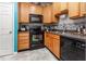 A well-lit kitchen is equipped with black appliances, natural wood cabinetry, and mosaic backsplash at 320 Gilman Ln # 106, Raleigh, NC 27610