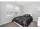 Carpeted bedroom with natural light and patterned comforter and pillows on a white bed frame at 512 Courtship Cv, Durham, NC 27703