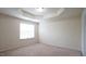 A bedroom has a decorative tray ceiling and a window allowing natural light at 5916 Longeria Ct, Raleigh, NC 27612