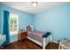 A light blue bedroom with wood floors, a white bed, and natural light from a window at 612 Agin Court Pl, Clayton, NC 27520