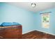 A light blue bedroom with a wooden dresser and natural light from a large window at 612 Agin Court Pl, Clayton, NC 27520