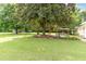 Expansive backyard showing mature trees, a pergola, and a building with a metal roof at 6200 Us-401 S, Bunnlevel, NC 28323
