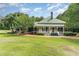 Charming home featuring a light yellow exterior, green metal roof, spacious porch, and lush green lawn at 6200 Us-401 S, Bunnlevel, NC 28323
