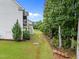 View of the side yard with a screened deck, lush green lawn and wooded area in the background at 7502 Latteri Ct, Raleigh, NC 27613