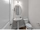 Charming half-bathroom featuring a pedestal sink, round mirror, and modern fixtures at 7502 Latteri Ct, Raleigh, NC 27613