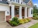 Inviting front porch with white pillars, brick accents, and beautifully landscaped flower beds at 7502 Latteri Ct, Raleigh, NC 27613