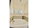 Bright bathroom featuring a soaking tub with tile surround and natural light from a window at 83 Mariners Point Way, Garner, NC 27529