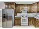 Classic kitchen design with wood cabinets, granite countertops, white backsplash, and stainless refrigerator at 835 Pearleman Teague Rd, Siler City, NC 27344