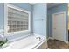 Bathroom featuring a soaking tub, glass block window, and blue walls at 853 Bluffcreek Dr, Fuquay Varina, NC 27526