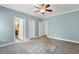 Carpeted bedroom with blue walls and multiple door openings to closets and bathrooms at 853 Bluffcreek Dr, Fuquay Varina, NC 27526