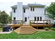 Back exterior view of a two-story home with a wooden deck and lush green lawn at 8841 Deerland Grove Dr, Raleigh, NC 27615