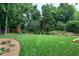 Lush backyard featuring a well-maintained lawn, privacy fence, mature trees, and playground at 8841 Deerland Grove Dr, Raleigh, NC 27615