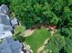 Large, verdant backyard featuring mature trees, a playground set, a deck, and outdoor seating for relaxation and play at 8841 Deerland Grove Dr, Raleigh, NC 27615