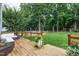 Spacious backyard showcasing a deck, a lush lawn, mature trees, and a playground area at 8841 Deerland Grove Dr, Raleigh, NC 27615