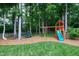 View of a backyard with a playground, grassy area, and tall trees at 8841 Deerland Grove Dr, Raleigh, NC 27615