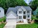 Beautiful two-story white home with a gray roof, attractive landscaping, and an attached two-car garage at 8841 Deerland Grove Dr, Raleigh, NC 27615