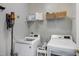 Well-organized laundry room with modern washer, dryer, shelving, and patterned wallpaper at 8841 Deerland Grove Dr, Raleigh, NC 27615