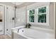 Bright bathroom has a soaking tub, glass-enclosed shower, and a window overlooking the trees at 8841 Deerland Grove Dr, Raleigh, NC 27615