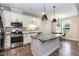 Bright kitchen with white cabinets, stainless steel appliances, large island with granite countertop, and breakfast nook at 9 Moss Side Ter, Durham, NC 27703