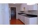 Open kitchen with white cabinetry, black countertops, and hardwood floors at 106 Knight Ct, Graham, NC 27253