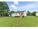 Expansive backyard featuring lush lawn, mature trees, and a house with wood steps to the yard at 107 Winter Ct, Selma, NC 27576