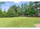 A grassy backyard with mature trees provides plenty of shade and room to run and play at 107 Winter Ct, Selma, NC 27576