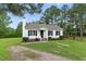 Charming white home featuring black shutters, a cozy front porch, and a well-maintained landscaped lawn at 107 Winter Ct, Selma, NC 27576
