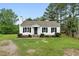 Charming white home with black shutters, a cozy front porch, and landscaped lawn under a clear blue sky at 107 Winter Ct, Selma, NC 27576