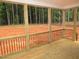 Covered porch with wooden railing and flooring, providing a serene outdoor view at 1155 Shonele Ln, Stem, NC 27581