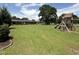Large backyard with a well-maintained lawn, mature trees, and a play structure at 12082 Nc 42, Fuquay Varina, NC 27526